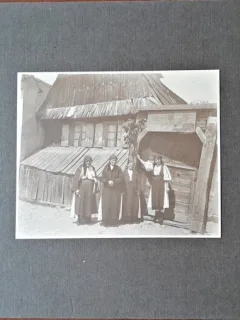 Fotografie pe carton, la tara in fata casei femei in costum popular, inceput de secol XX