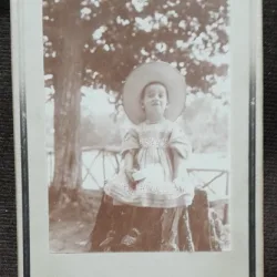 Fotografie pe carton, fetita la Slanic, asezata pe o bututuga, perioada interbelica